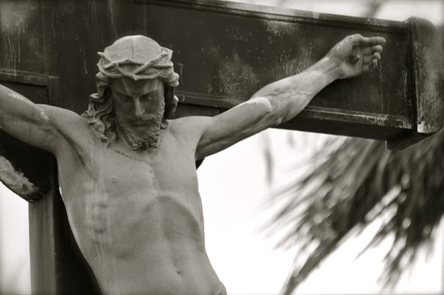Crucifixo de pedra, em preto e branco, com a cabeça de Cristo inclinada