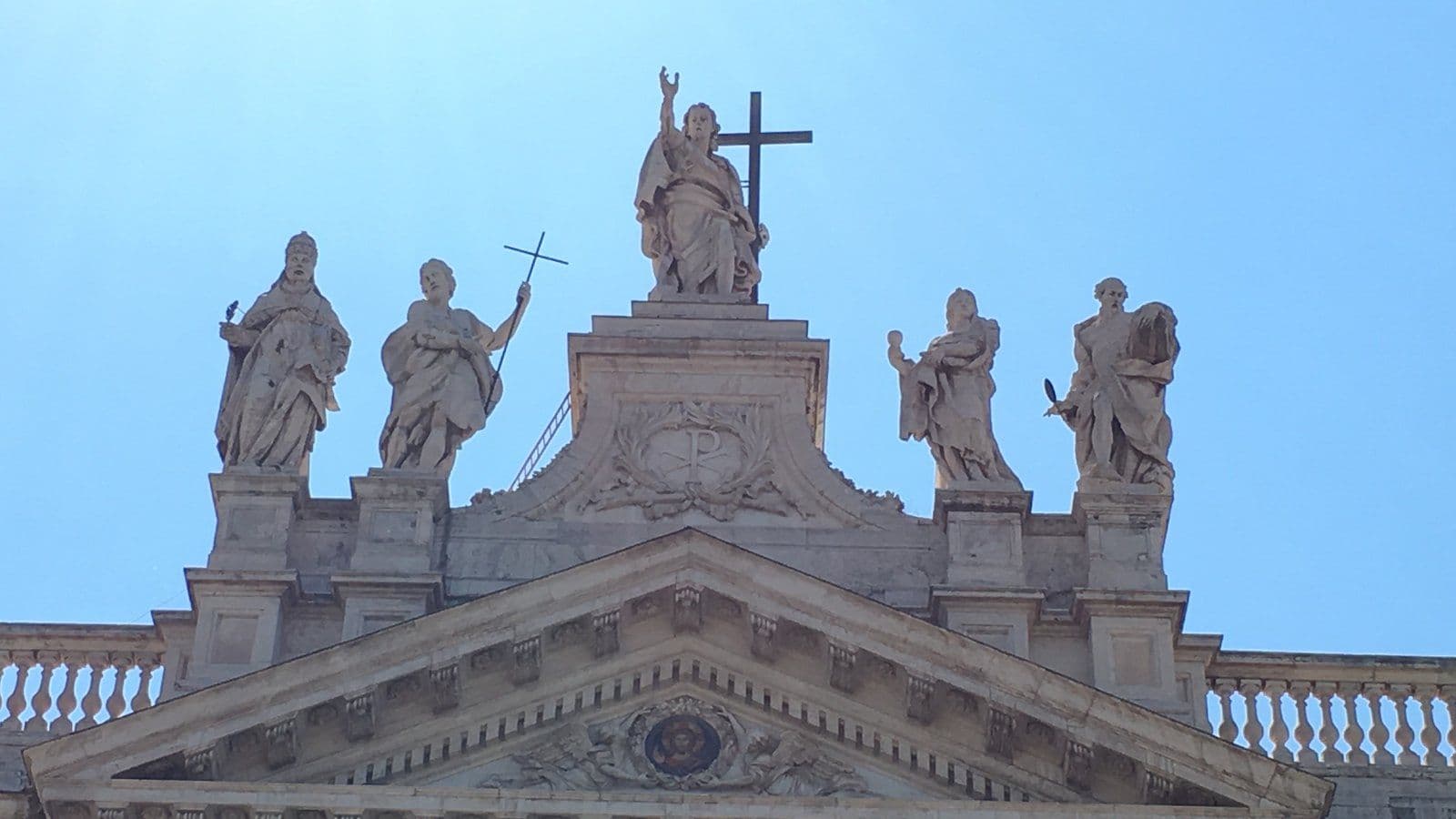 Estátuas de Cristo Salvador e dos apóstolos no alto da fachada de uma basílica