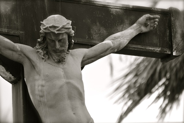 Crucifixo de pedra, em preto e branco, com a cabeça de Cristo inclinada